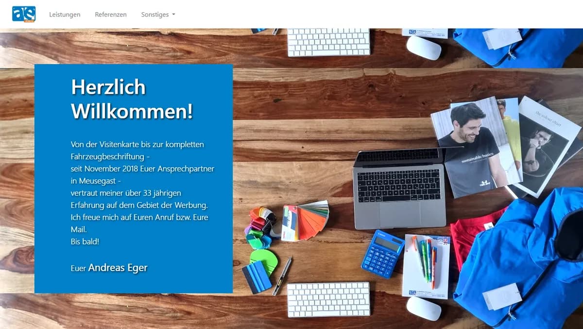 ae-werbung-meusegast.de homepage with a welcome text on a wooden desk full of promotional products